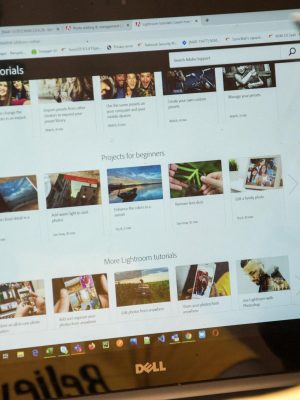 A woman exploring Adobe Lightroom tutorials online for learning and photo editing.